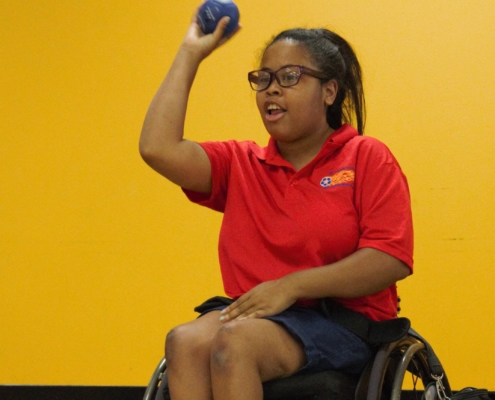 woman in wheelchair preparing to throw a boccia ball