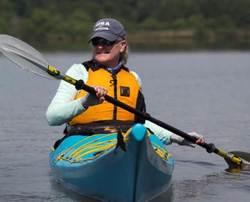 ashley thomas paddling in a blue kayak on lake crabtree